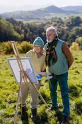 Senior couple painting surrounded autumn nature. - HPIF01364