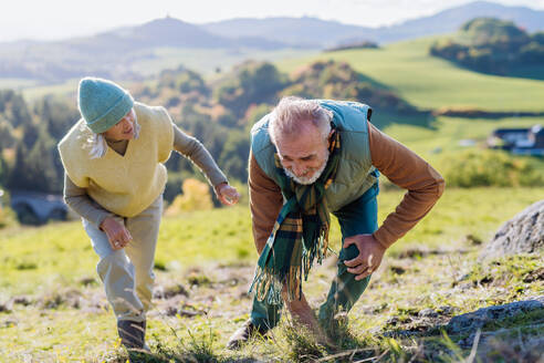 Senior man having painful knee during autumn walk, his wife taking care of him. - HPIF01367