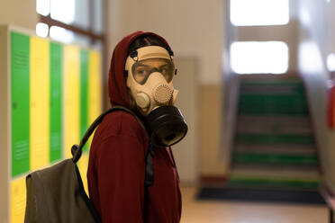 A young student in gas mask looking at camera at school. - HPIF01431