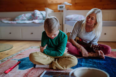 Ein Junge mit Down-Syndrom sitzt auf dem Boden und spielt mit seiner Großmutter zu Hause - HPIF01451