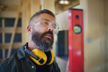 Carpenter checking a wooden planks with spirit level, diy eco-friendly homes concept. - HPIF01534