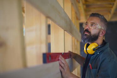 Carpenter checking a wooden planks with spirit level, diy eco-friendly homes concept. - HPIF01539