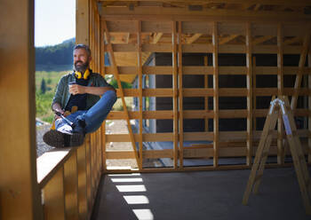 Ein Handwerker, der sich ausruht und eine Pause macht, während er auf einer Holzbaustelle arbeitet, diy eco-friendly homes concept. - HPIF01543