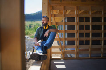 Ein Handwerker, der sich ausruht und eine Pause macht, während er auf einer Holzbaustelle arbeitet, diy eco-friendly homes concept. - HPIF01544