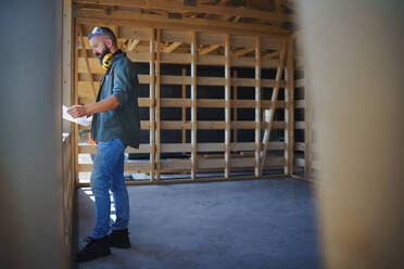 Handwerker, die Baupläne bearbeiten und auf einer Holzbaustelle arbeiten, umweltfreundliches Heimwerker-Konzept. - HPIF01550