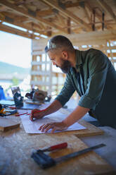 Construction worker smiling, drawing and checking a blueprints, diy eco-friendly homes concept. - HPIF01554