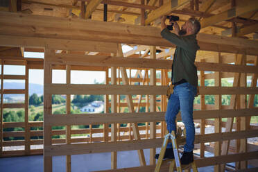 A construction worker working with screwdriver on wooden frame, diy eco-friendly homes concept. - HPIF01557