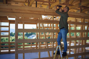 Ein Bauarbeiter arbeitet mit Schraubenzieher auf Holzrahmen, diy umweltfreundliche Häuser Konzept. - HPIF01557