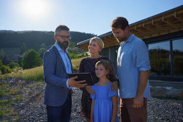 A sales Agent showing plans of new house to young family on construction site. - HPIF01574