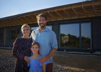 Junge Familie vor ihrem ökologischen Holzhaus, Konzept der Nachhaltigkeit und des gesunden Lebens. - HPIF01575