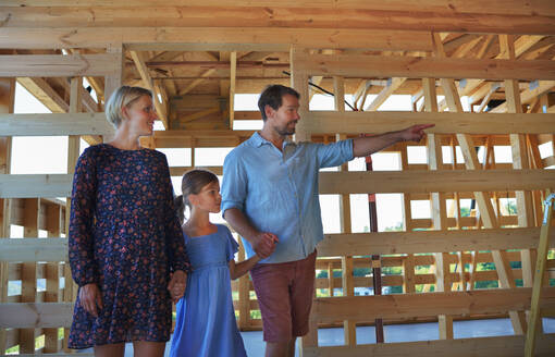 Eine junge Familie auf der Baustelle im Rahmen eines neuen Hauses. - HPIF01578