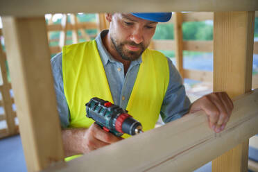 Ein Bauarbeiter arbeitet mit Schraubenzieher auf Holzrahmen, diy umweltfreundliche Häuser Konzept. - HPIF01608