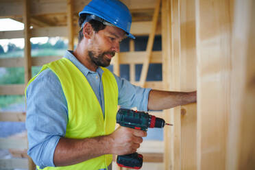 Ein Bauarbeiter arbeitet mit Schraubenzieher auf Holzrahmen, diy umweltfreundliche Häuser Konzept. - HPIF01609