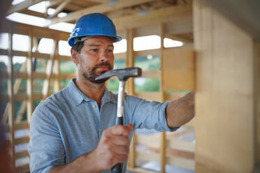 A construction worker working with screwdriver on wooden frame, diy eco-friendly homes concept. - HPIF01613