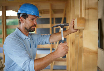 Ein Bauarbeiter arbeitet mit Schraubenzieher auf Holzrahmen, diy umweltfreundliche Häuser Konzept. - HPIF01614