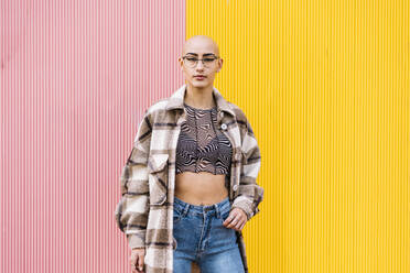 Young woman wearing plaid jacket standing in front of colored wall - DAMF01165