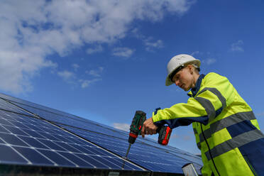 Eine Ingenieurin bei der Installation von Fotovoltaik-Solarzellen auf dem Dach, Konzept für alternative Energien. - HPIF01625