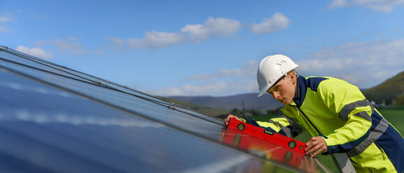 Eine Ingenieurin bei der Installation einer Photovoltaikanlage auf dem Dach, alternatives Energiekonzept. - HPIF01628