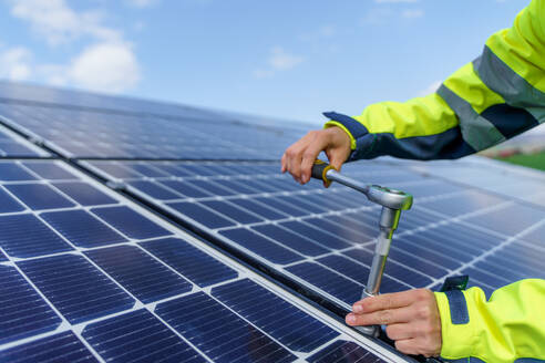 A close-up of woman engineer installing solar photovoltaic panels on roof, alternative energy concept. - HPIF01632