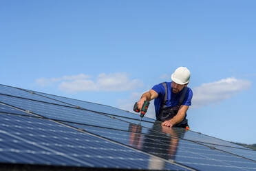 Ein Mann Arbeiter Installation von Solar-Photovoltaik-Panels auf dem Dach, alternative Energie-Konzept. - HPIF01633