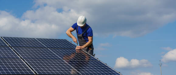 Ein Mann Arbeiter Installation von Solar-Photovoltaik-Panels auf dem Dach, alternative Energie-Konzept. - HPIF01634
