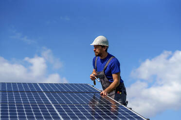 Ein Mann Arbeiter Installation von Solar-Photovoltaik-Panels auf dem Dach, alternative Energie-Konzept. - HPIF01635