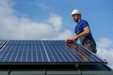 Ein Mann Arbeiter Installation von Solar-Photovoltaik-Panels auf dem Dach, alternative Energie-Konzept. - HPIF01637