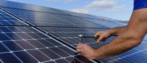 Ein Mann Arbeiter Installation von Solar-Photovoltaik-Panels auf dem Dach, alternative Energie-Konzept. Close up Hände mit Bohrer. - HPIF01641