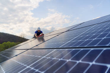 A man worker installing solar photovoltaic panels on roof, alternative energy concept. - HPIF01648