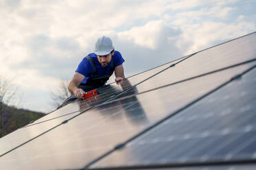 Ein Mann Arbeiter Installation von Solar-Photovoltaik-Panels auf dem Dach, alternative Energie-Konzept. - HPIF01649