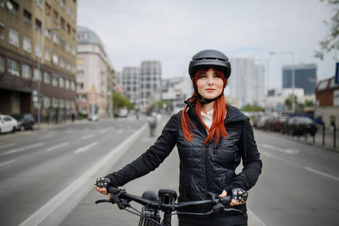 A portrait of businesswoman commuter on the way to work with bike, sustainable lifestyle concept. - HPIF01728