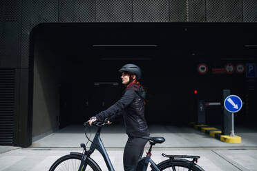 A portrait of businesswoman commuter on the way to work with bike looking at camera, sustainable lifestyle concept. - HPIF01731