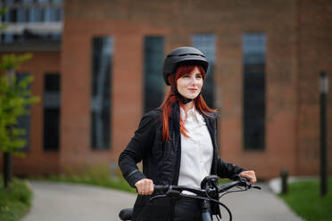 A portrait of businesswoman commuter on the way to work with bike, sustainable lifestyle concept. - HPIF01736