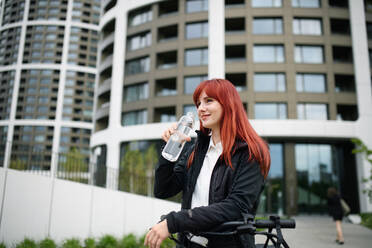 Porträt einer Geschäftsfrau auf dem Weg zur Arbeit mit Fahrrad und Trinkwasser, Konzept des nachhaltigen Lebensstils. - HPIF01737