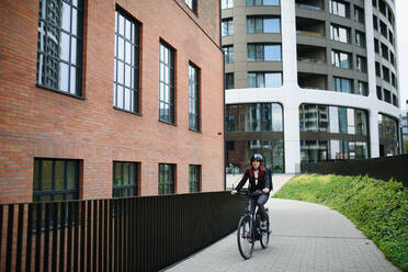 Eine Geschäftsfrau auf dem Weg zur Arbeit mit dem Fahrrad, nachhaltiges Lifestyle-Konzept. - HPIF01750