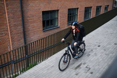 A businesswoman commuter on the way to work with bike, sustainable lifestyle concept. High angle view. - HPIF01751