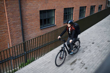 Eine Geschäftsfrau auf dem Weg zur Arbeit mit dem Fahrrad, Konzept des nachhaltigen Lebensstils, Weitwinkelansicht. - HPIF01751