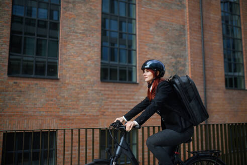 A businesswoman commuter on the way to work with bike, sustainable lifestyle concept. - HPIF01752