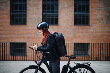 Porträt einer Geschäftsfrau, die mit dem Fahrrad zur Arbeit fährt, Konzept des nachhaltigen Lebensstils. - HPIF01757