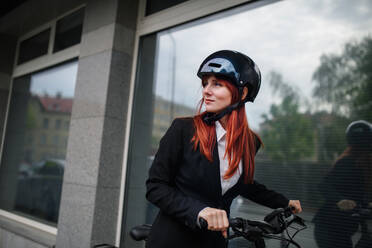 Porträt einer Geschäftsfrau, die mit dem Fahrrad zur Arbeit fährt, Konzept des nachhaltigen Lebensstils. - HPIF01758
