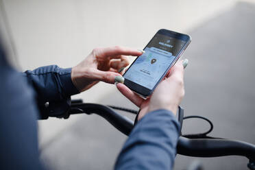 Ein Kurier auf dem Fahrrad, der auf sein Handy schaut und eine App für die Zustellung benutzt, nachhaltiges Verkehrskonzept - HPIF01760