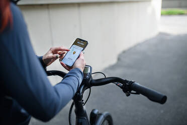 Ein Kurier auf dem Fahrrad, der auf sein Handy schaut und eine App für die Zustellung benutzt, nachhaltiges Verkehrskonzept - HPIF01761