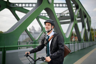 A businessman commuter on the way to work, riding bike over bridge, sustainable lifestyle concept. - HPIF01766