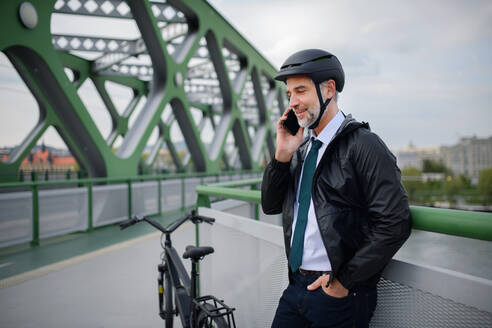 Ein Geschäftsmann auf dem Weg zur Arbeit, auf einer Brücke, der mit seinem Handy telefoniert, nachhaltiges Lifestyle-Konzept. - HPIF01770