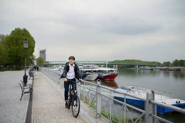 A businessman commuter on the way to work, riding bike over bridge, sustainable lifestyle concept. - HPIF01802