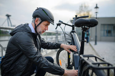 Portrait of businessman in the bicycle helmet fixing his bike, sustainable lifestyle concept. - HPIF01812