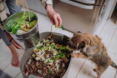 Eine Frau wirft Gemüseschnipsel in einen Kompostkübel in der Küche. - HPIF01850