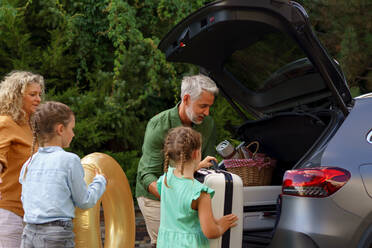 A fmily with little children loading car and waiting for charging car before going on holiday. - HPIF01869