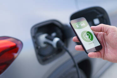 Man setting phone application for charging his electric car at a charging station, closeup. - HPIF01896