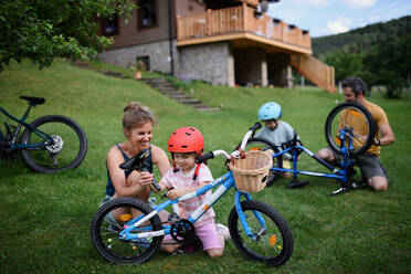Eine junge Familie mit kleinen Kindern bereitet sich auf eine Fahrradtour vor dem Haus vor. - HPIF01958